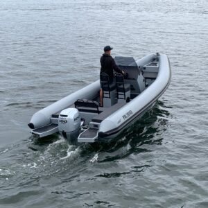 RIB-båt med Honda 100 hk utenbordsmotor i bevegelse på vannet, med en fører ved styrekonsollen.